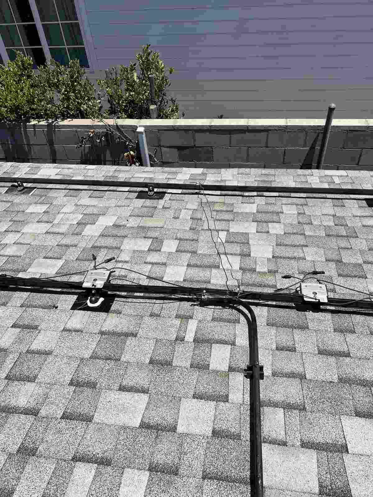 Shingle roof with exposed equipment rails, brackets and cables.
