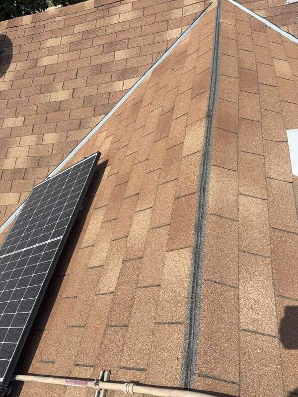 Brown shingle roof ridges and valleys beside part of an existing solar panel